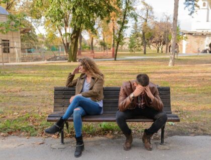 Two people sitting on a bench, arguing.