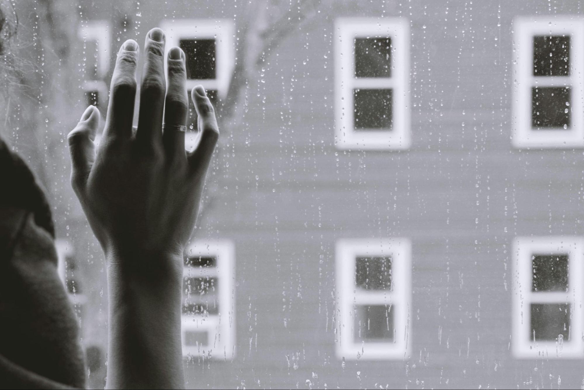  Person holding their hand on a window